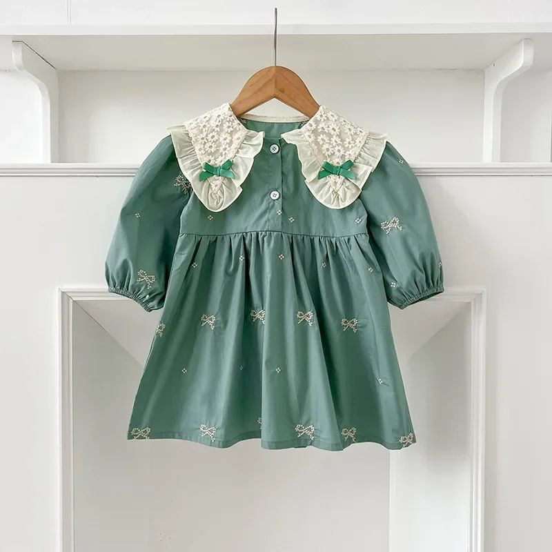 Haze Green dress with a cream lace collar and embroidered bow motifs on a hanger