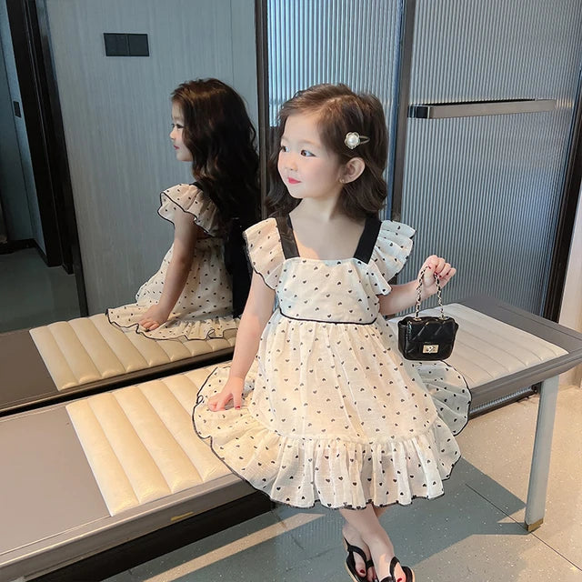 Girl wearing the cotton heart-print dress with ruffled shoulders and a flared skirt