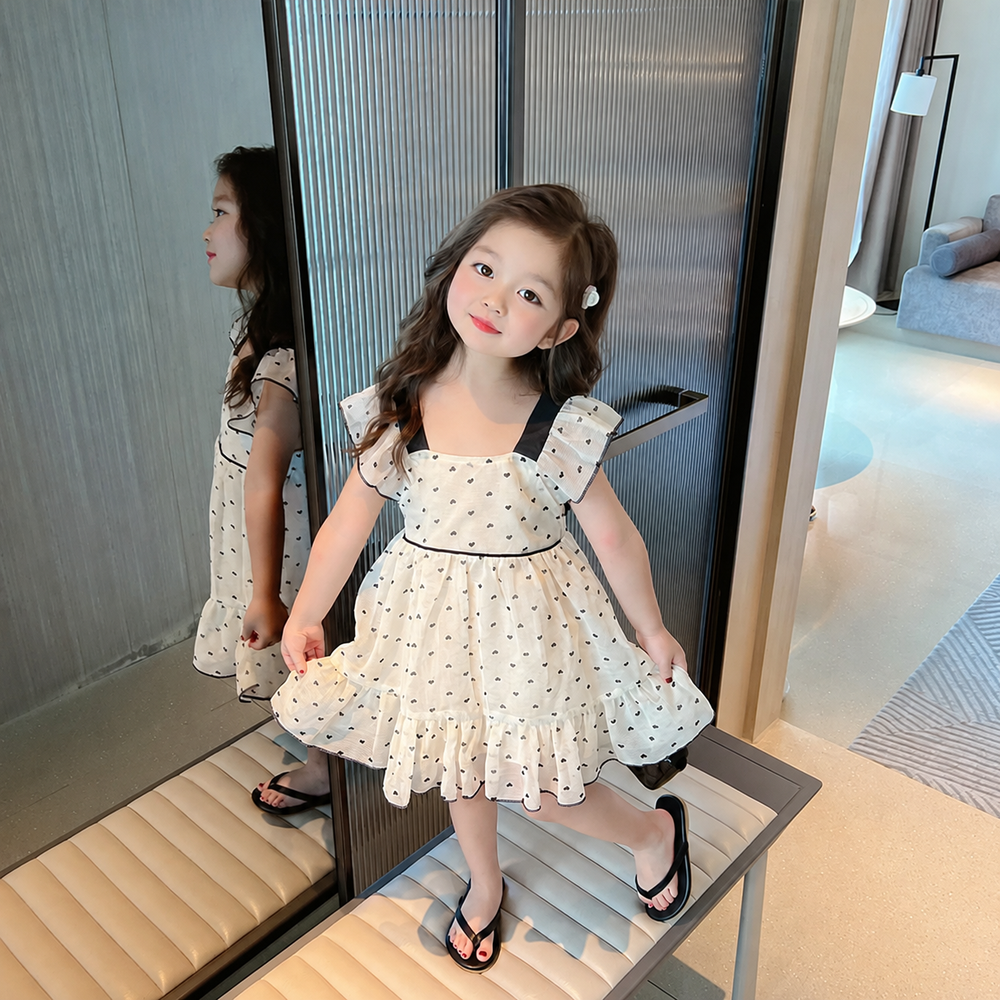 Girl holding out the skirt of a heart-print summer dress with a ruffled hem