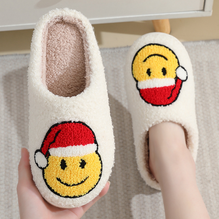 Cream slippers featuring yellow smiley faces wearing red Santa hats.