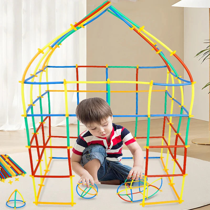 Child sitting inside a house-shaped build made with colorful tubes and connectors