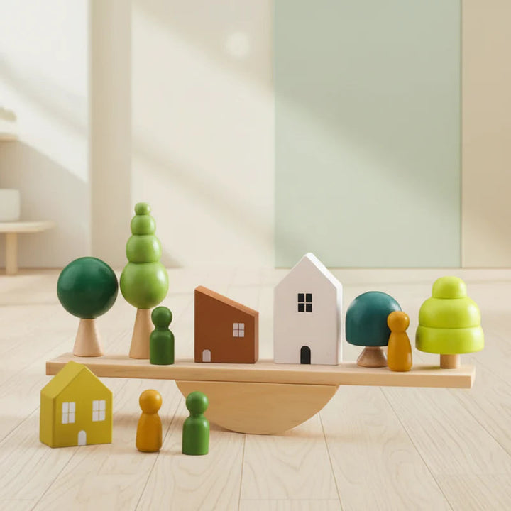 Painted wooden houses, trees, and figures arranged on a curved-base balance board