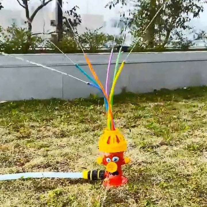 Flexible tubes spraying water from a hydrant sprinkler connected to a garden hose on the lawn