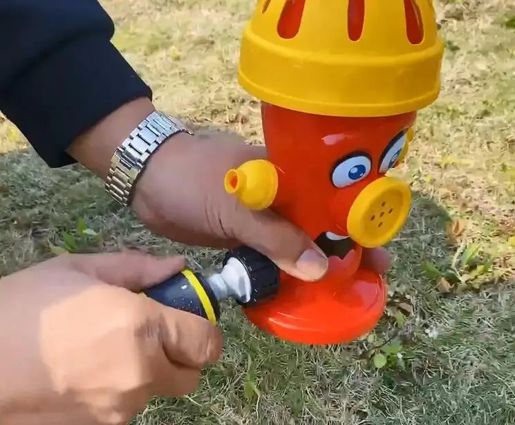 Hands attaching a garden hose connector to the side of a red hydrant sprinkler