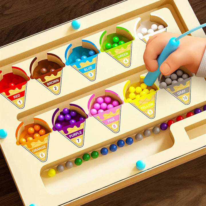 Hand guiding yellow beads into an ice cream cone with a magnetic pen
