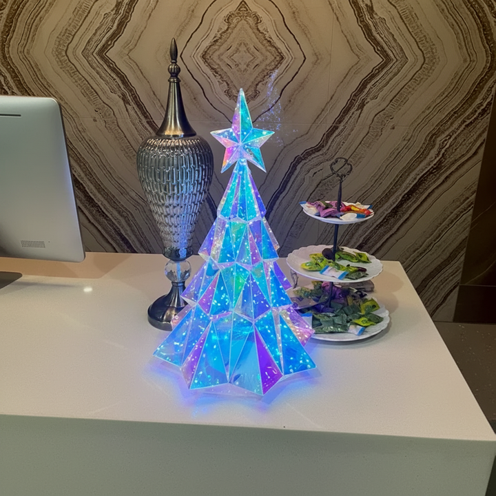 Star-topped LED Christmas tree on a white counter beside a tiered serving tray