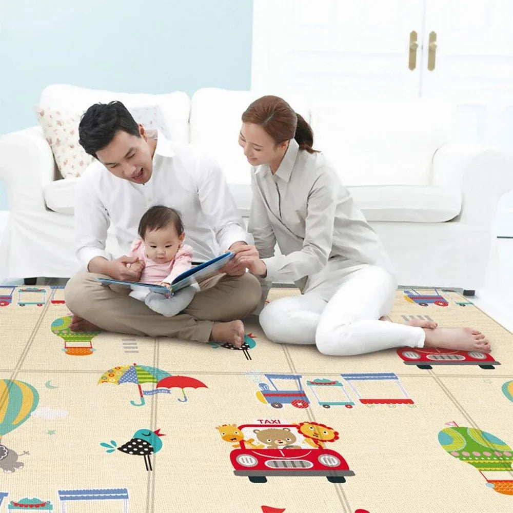 Two adults and a baby sharing a book while sitting on an illustrated foam play mat