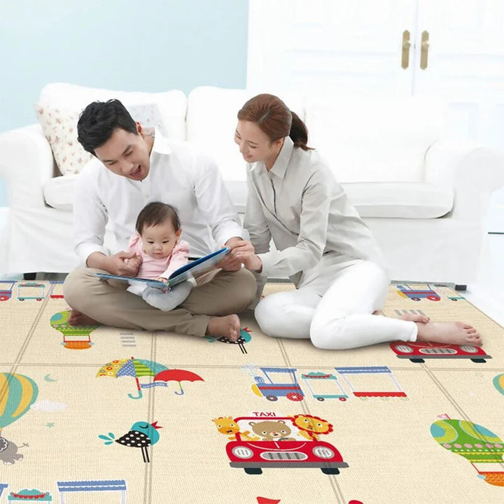 Two adults and a baby sharing a book while sitting on an illustrated foam play mat