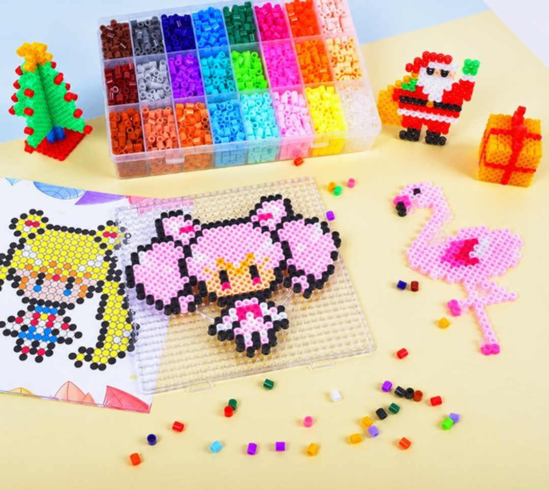 Ironing bead art with a flamingo, owl, Christmas tree, and gift beside a tray of sorted beads