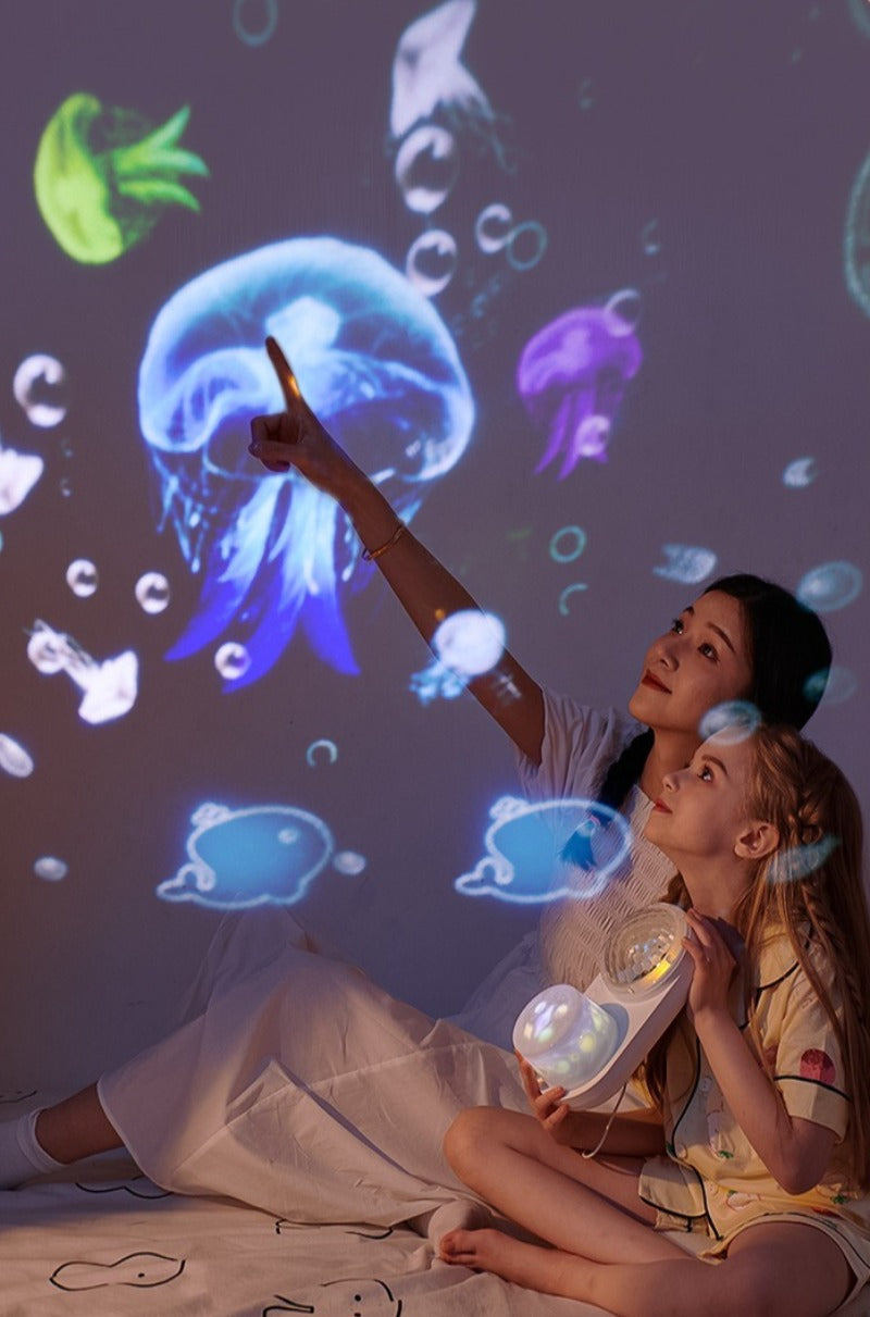 A woman and child looking at jellyfish and bubble projections on a bedroom wall.
