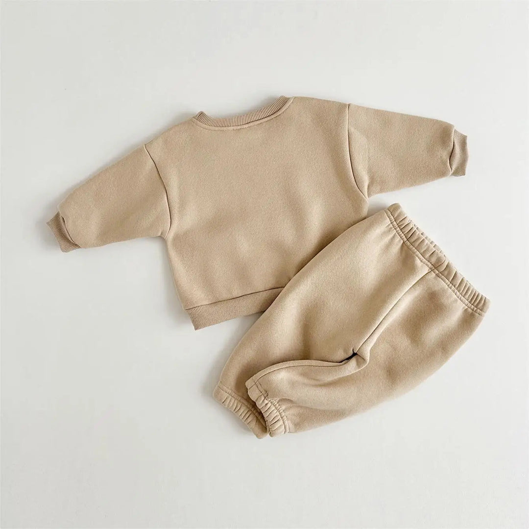 Back of a khaki baby sweater beside matching pants with an elastic waistband