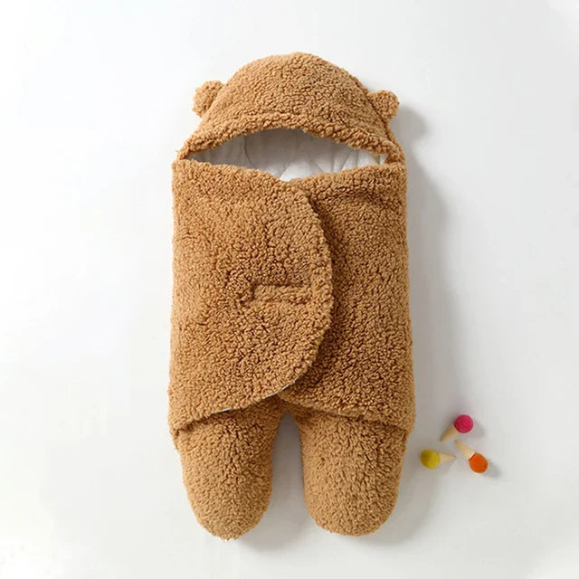 Khaki sherpa baby wrap blanket with a bear-ear hood and overlapping front wings.