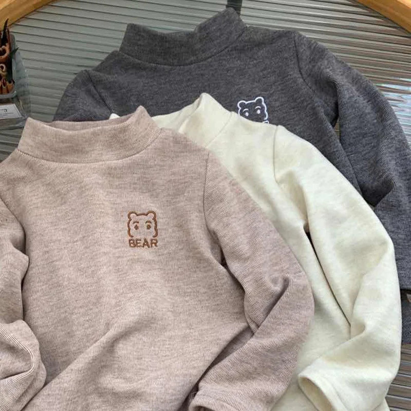 Khaki bear fleece shirt in front of beige and dark gray shirts