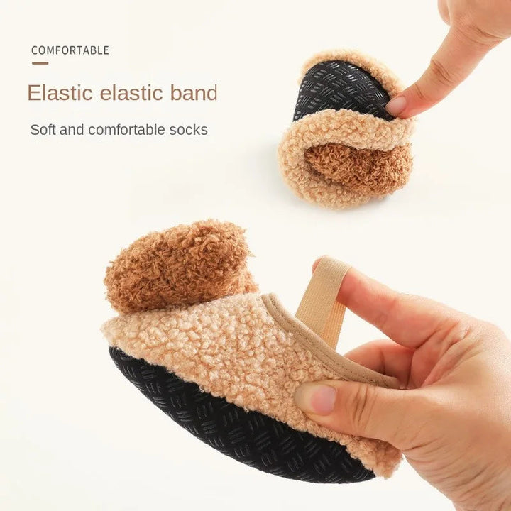 Hands bending a khaki bear slipper to show its flexible sole and elastic band