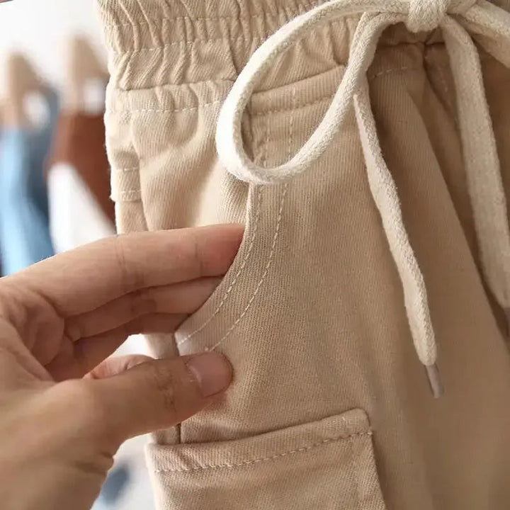 Khaki cargo pants showing a curved front pocket and flap cargo pocket