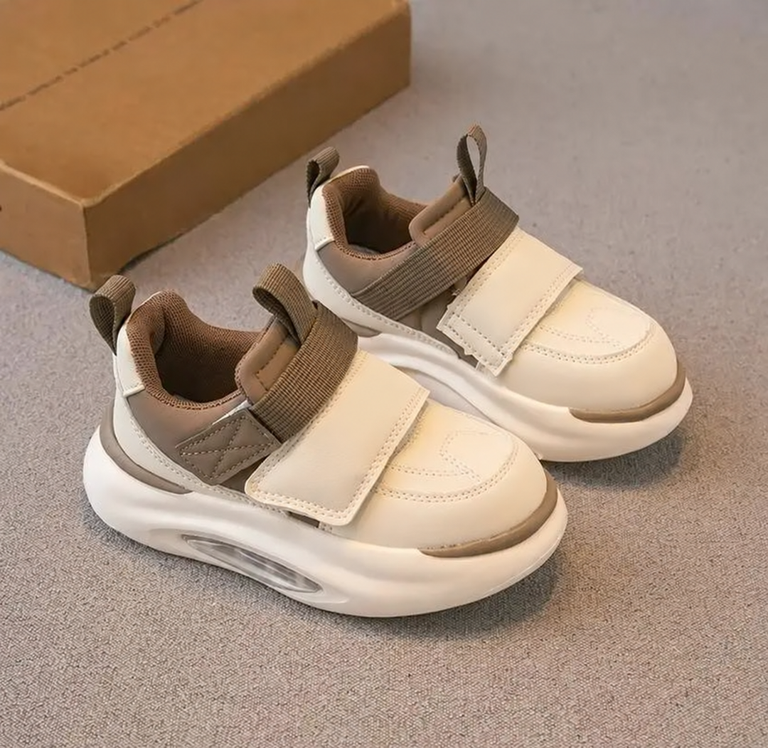 Pair of khaki and cream sneakers with wide front straps and sculpted white soles