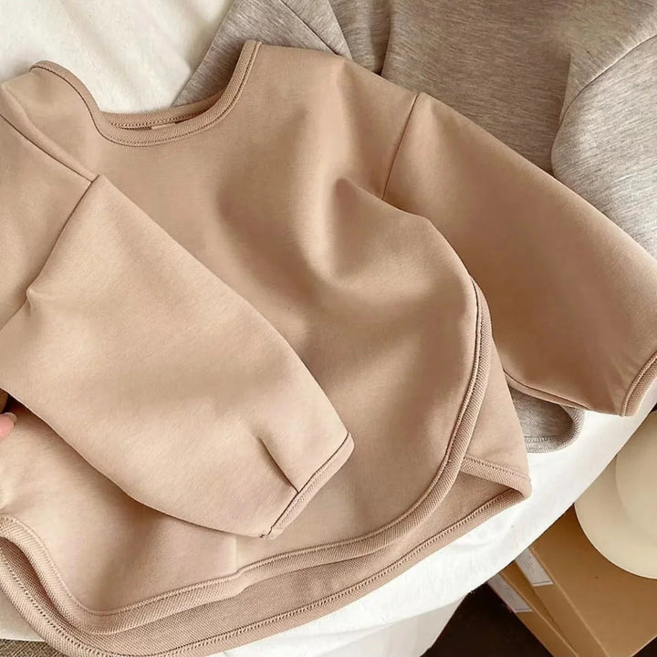 Khaki sweater close-up showing the crew neckline, long sleeves, and curved hem