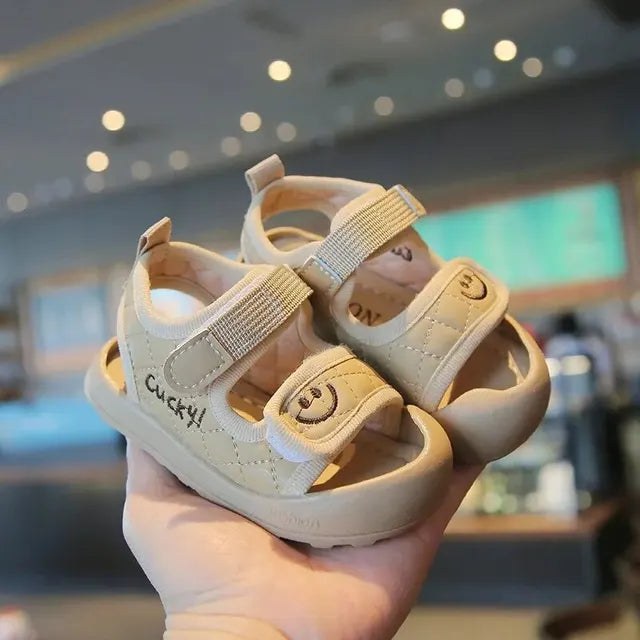 Khaki sandals held together to show the side openings and broad front straps.