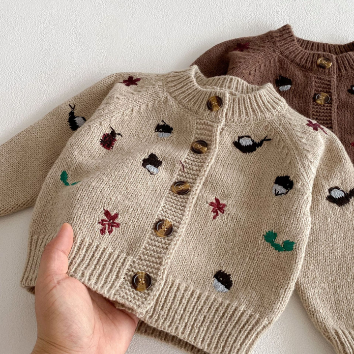 Close-up of a khaki cardigan showing colorful motifs, ribbed trim and front buttons