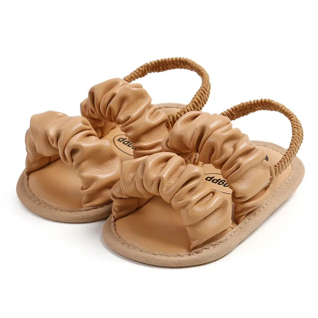 Khaki baby sandals with ruched straps, open toes, and tan soles