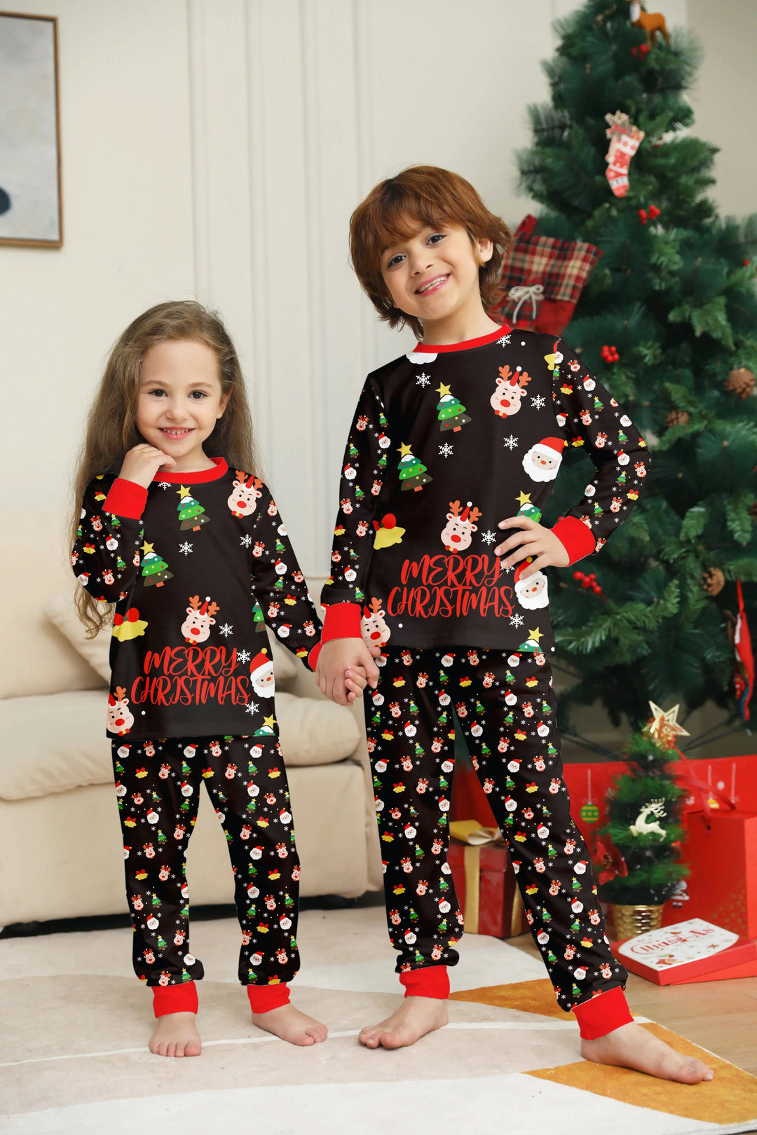 Two children in matching black Christmas pajama tops and pants with red cuffs