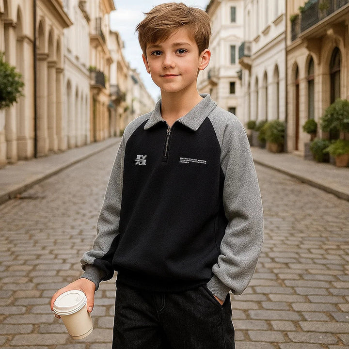 Child wearing a black sweater with gray sleeves and a gray collar on a cobblestone street.