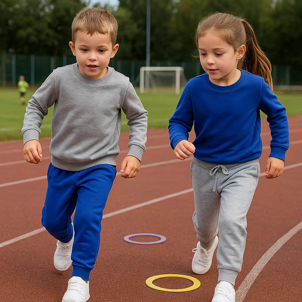 Two children wearing blue and gray jogger pants while running on an outdoor track