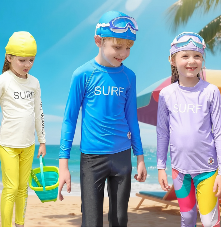Three children wearing cream, blue, and lavender long-sleeve swim shirts at the beach