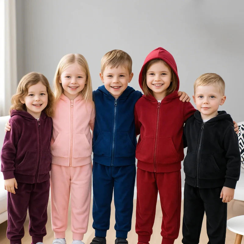 Five children wearing purple, pink, navy, red, and black zip-up tracksuits
