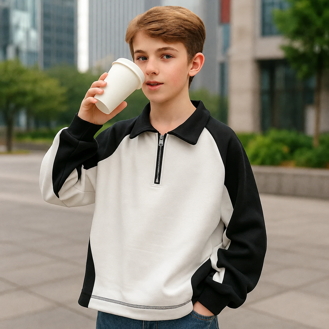 Front view of a child wearing a white and black quarter-zip sweater outdoors.
