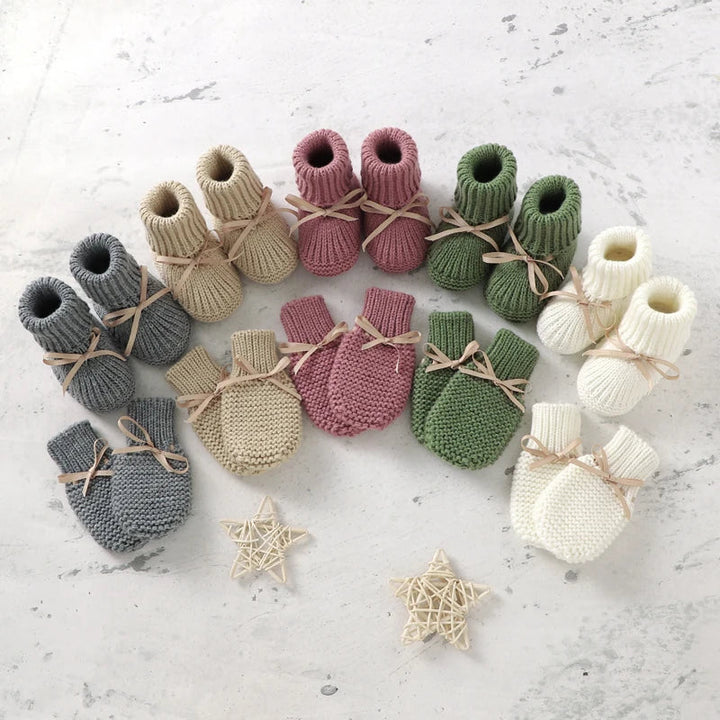 Knitted baby booties and mittens arranged in gray, beige, pink, green and white