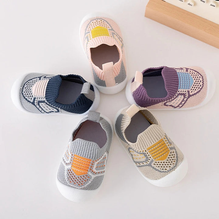 Five knit slip-on shoes in blue, pink, purple, gray, and beige arranged in a circle