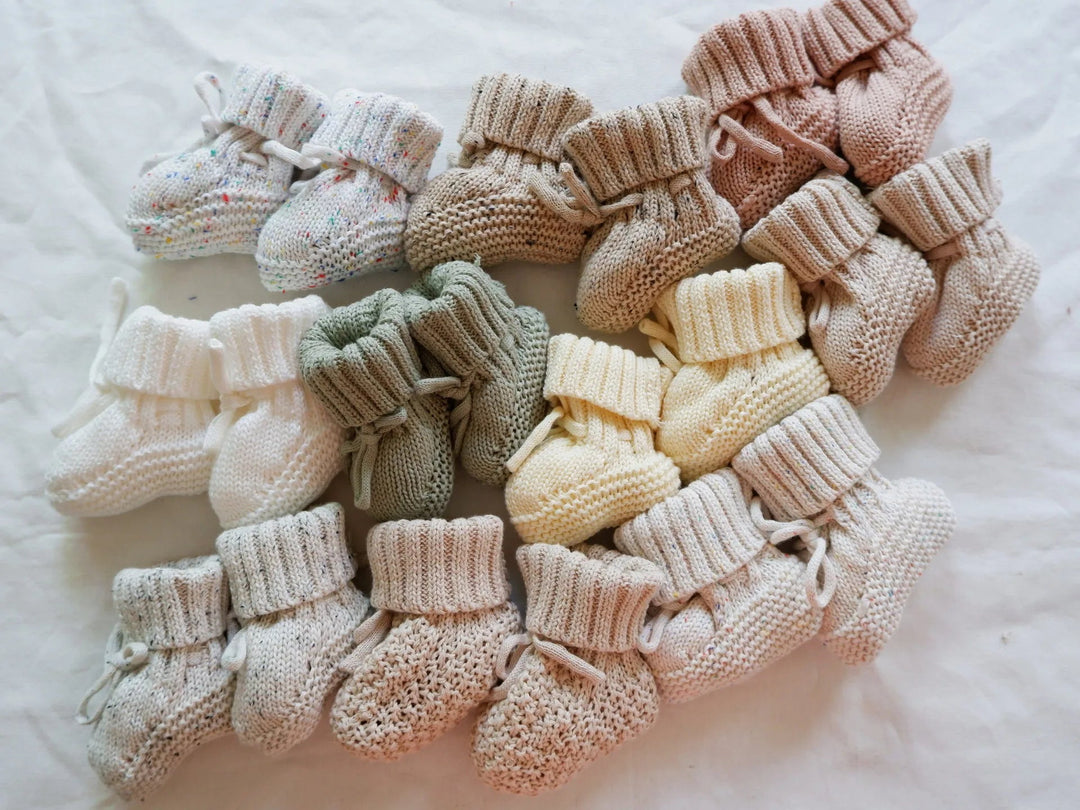 Assorted baby booties with folded ribbed cuffs, textured knitting, and ankle ties.