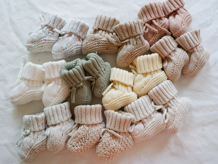 Assorted baby booties with folded ribbed cuffs, textured knitting, and ankle ties.