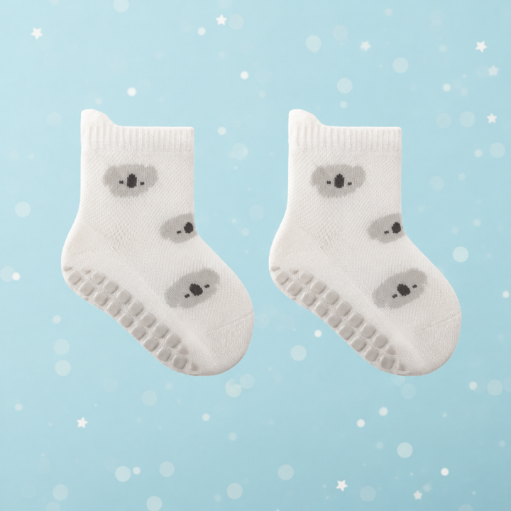 Pair of white koala-pattern baby socks with gray grip dots along the soles.