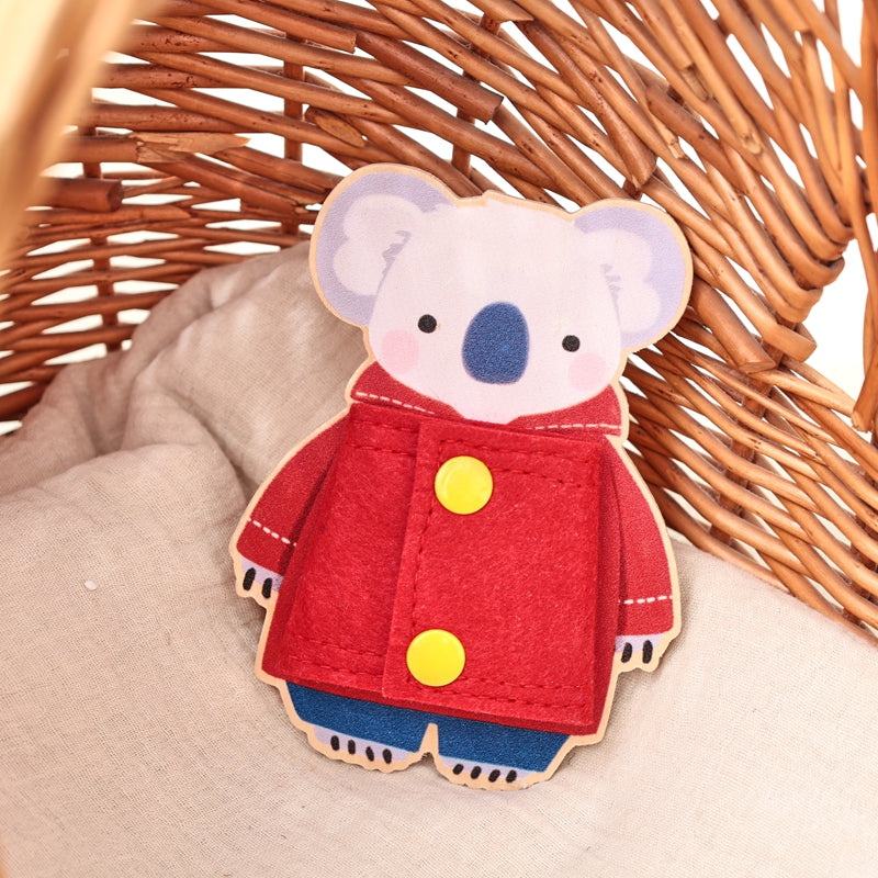 Koala dressing board with a red fabric coat and two yellow snap fasteners on a cushion