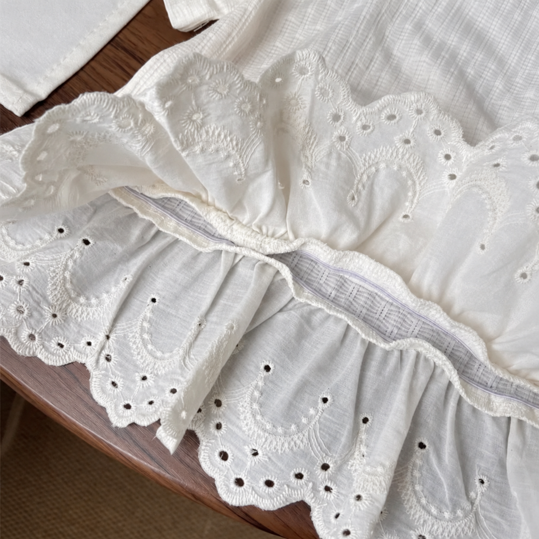 Detail of the gathered lace-hem seam and eyelet embroidery on the white T-shirt.