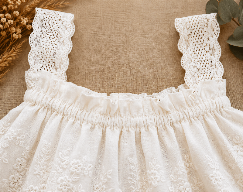 Close-up of wide lace straps and the gathered neckline on the white top