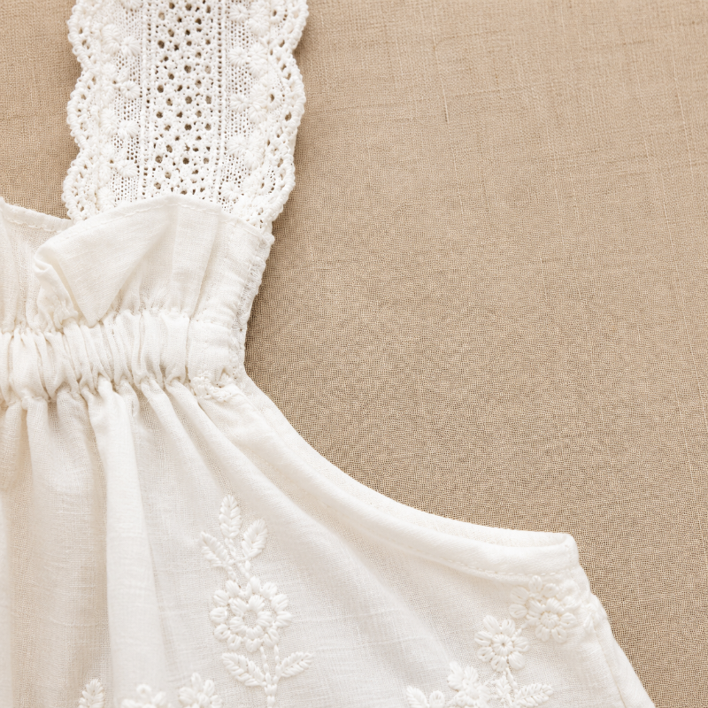 Side detail of the white top showing a lace strap, gathered neckline, and arm opening