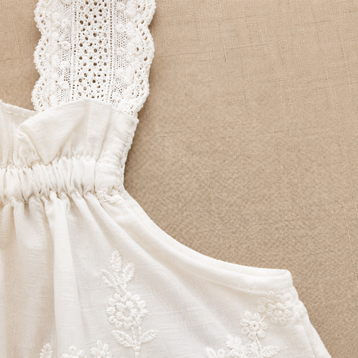Side detail of the white top showing a lace strap, gathered neckline, and arm opening
