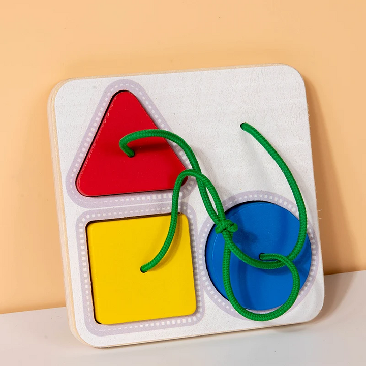 Wooden shape-matching board with a red triangle, yellow square, blue circle, and green lacing cord.
