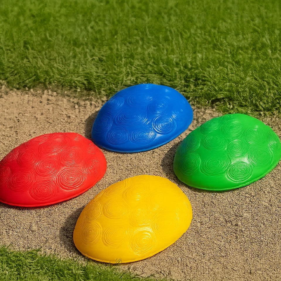 Four large red, blue, green, and yellow stepping stones arranged outdoors beside grass