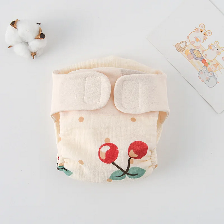 Cloth diaper with large red cherries and a cream hook-and-loop waistband
