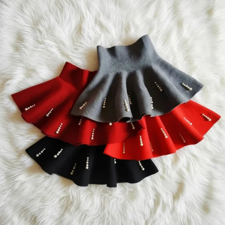 Layered gray, red, and black knit skirts with vertical rows of pearl-style beads