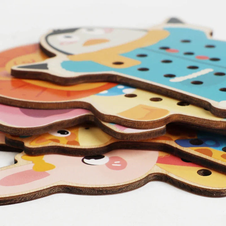 Stacked wooden animal lacing boards showing their edges and threading holes
