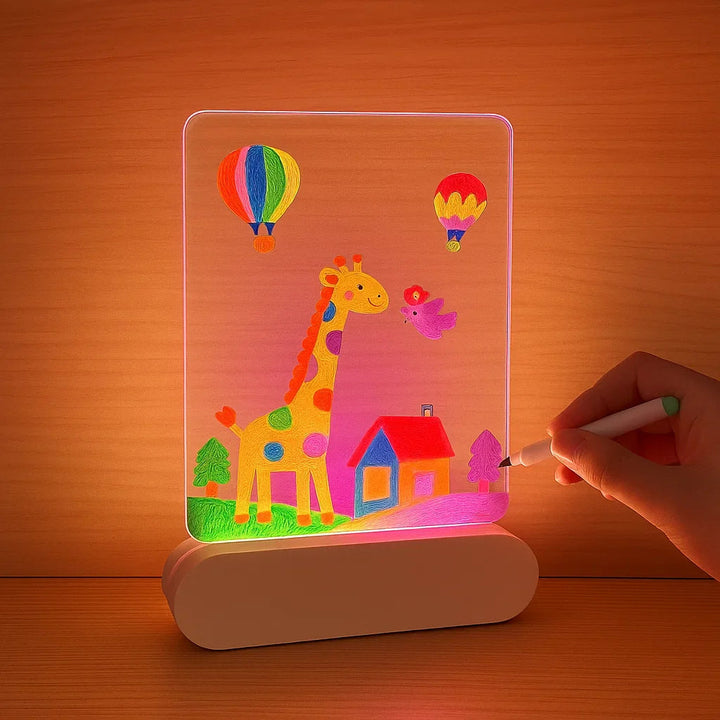Hand adding details to a glowing giraffe and house drawing on an LED drawing board