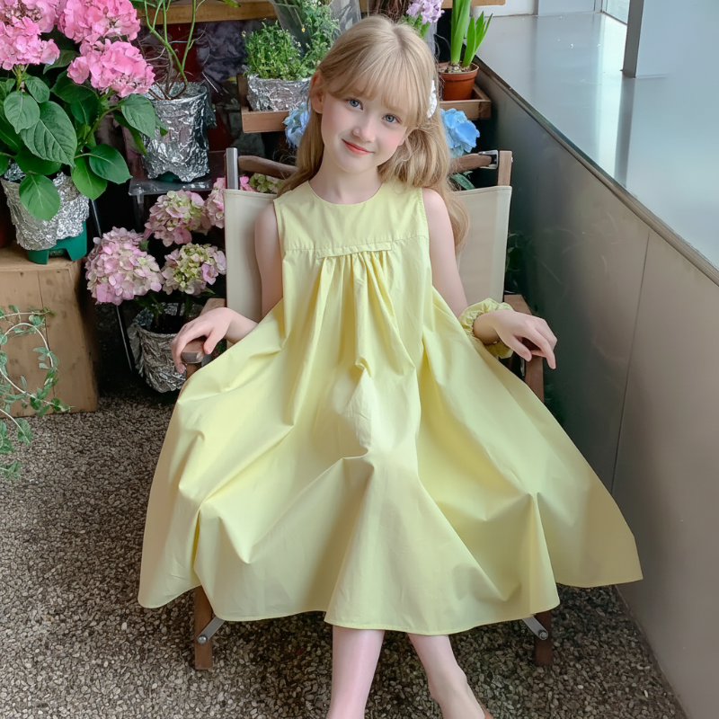 Girl holding out the skirt of a lemon-yellow sleeveless dress while seated