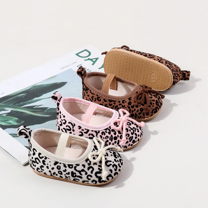 White, pink, and brown leopard-print baby shoes arranged to show bows and the textured outsole