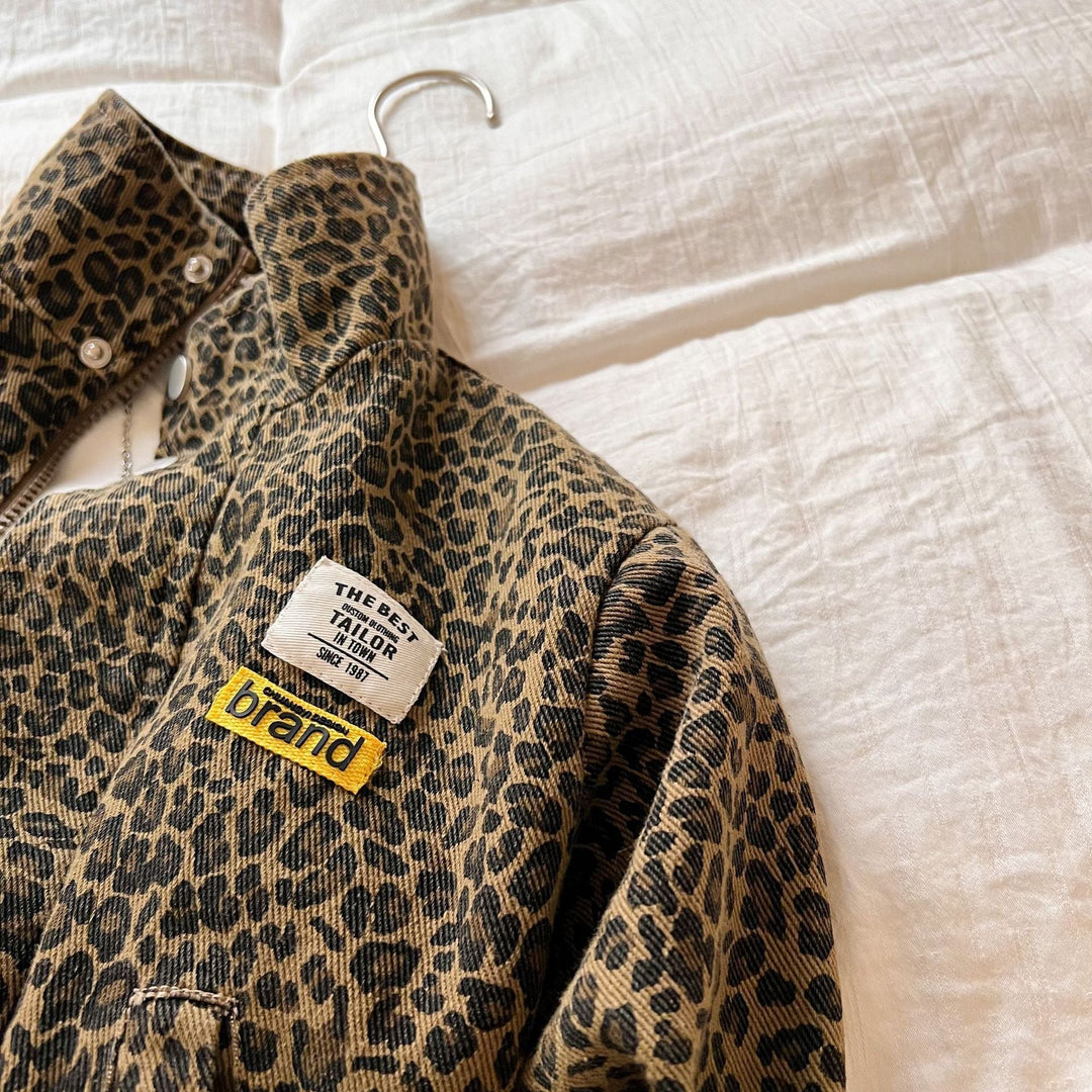 Close-up of brown leopard print jacket fabric, stand collar, and sewn chest patches