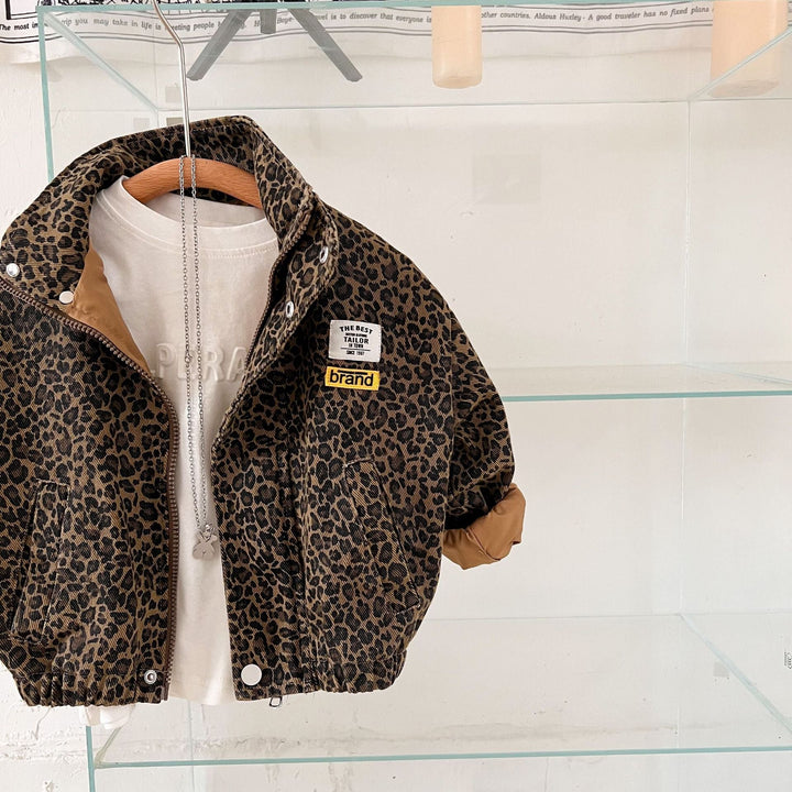 Leopard print jacket hanging in front of glass shelves, with rolled cuffs and a white shirt